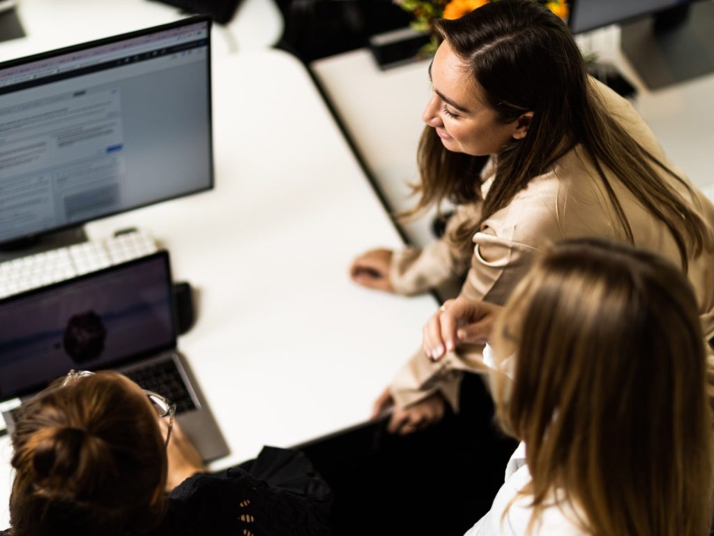 3 personer som står foran en PC-skjerm.